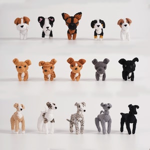 May include: A collection of fifteen handmade crochet dog figurines in various breeds and colours. The dogs are displayed on a white surface, showcasing their unique features and poses. Each dog is approximately 7.6 cm tall.