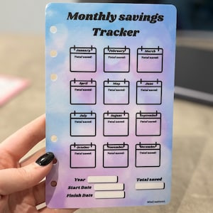 May include: A printable monthly savings tracker with a blue and purple ombre background. The tracker includes a calendar for each month of the year, with space to write in the total saved for each month. There are also spaces to write in the year, start date, and finish date.
