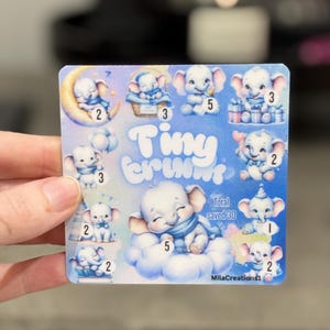 May include: A square sticker with illustrations of white baby elephants with blue accents. The sticker has the words "Tiny Trunks" in a light blue font. Each elephant has a number next to it. The sticker says "Total saved 30" and "MilaCreations1".