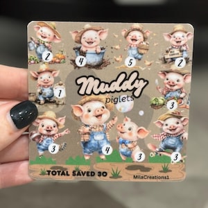 May include: A square sticker featuring illustrations of cartoon piglets in overalls and straw hats. The sticker has the text "Muddy piglets" and "TOTAL SAVED 30". Each piglet has a number from 1 to 5.