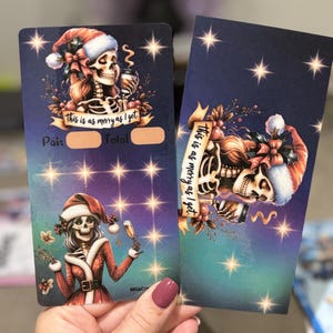 May include: Two festive cards with skeleton illustrations. One card depicts a skeleton in a Santa hat holding a drink, with the text "This is as merry as I get." The other card has a similar design. Both cards have a dark blue background with star accents.