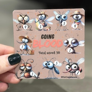 Op de afbeelding: Een rechthoekige kaart met genummerde cartoonmuggen. De kaart heeft de woorden "GOING BLOOD" en "Total saved 30". De kaart wordt vastgehouden door een persoon met donkergroene nagellak.