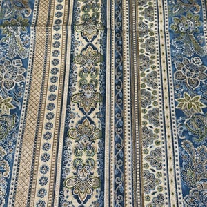 May include: A fabric textile featuring a repeating vertical stripe pattern in shades of blue, cream, and olive green. The design includes intricate floral motifs, paisley-like shapes, diamond cross-hatching, and small circular flower borders.
