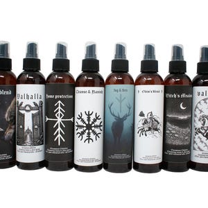 May include: Ten amber plastic spray bottles arranged in a row, each featuring a unique black and white label with distinct titles including Haunted Juniper, Feral Blend, Valhalla, Home Protection, Cleanse & Banish, Fog & Fern, Odin's Blood, Witch's Meadow, Valkyrie, and Dark Forest.