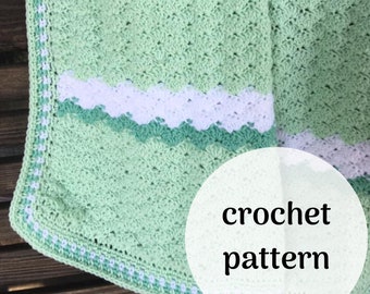 May include: A crochet pattern for a green and white baby blanket with a scalloped border. The blanket is made with a textured stitch and has a white and green stripe in the center.