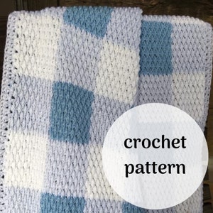 May include: A crochet pattern for a baby blanket with a checkered design in white, light blue, and gray.