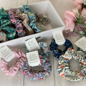 May include: A set of 10 mini scrunchies in various floral patterns. The scrunchies are made of soft fabric and are perfect for adding a touch of style to any hairstyle. The scrunchies are packaged in a clear plastic bag with a white label that reads "Lizzyman Mini Scrunchie Set".