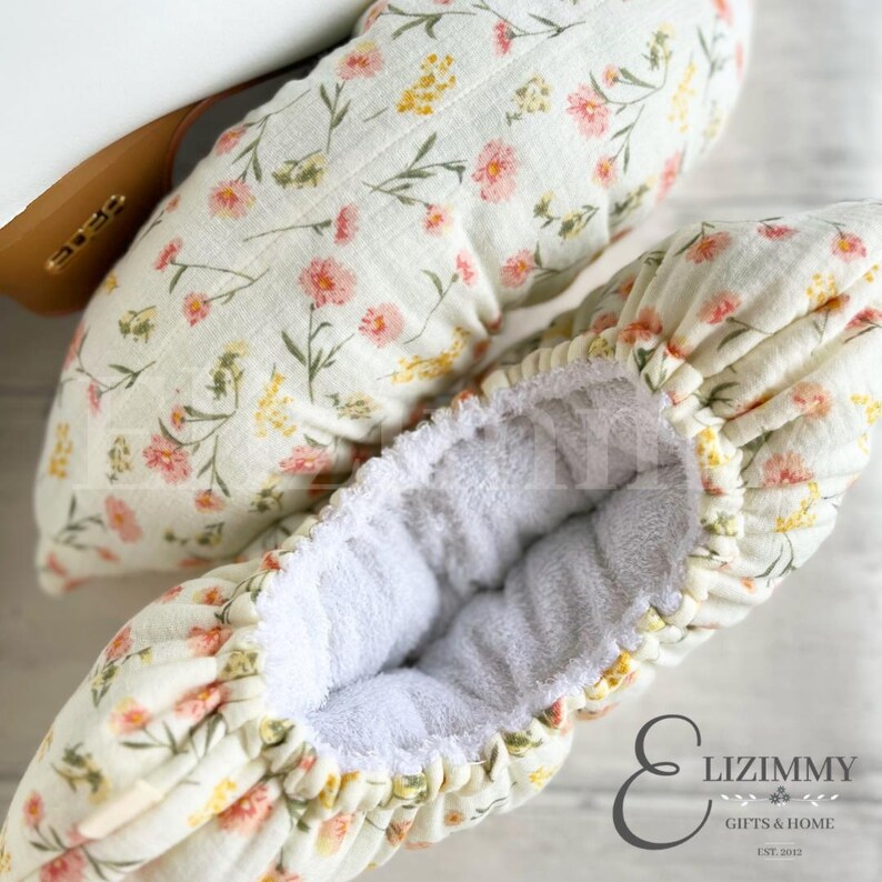 May include: A pair of white and yellow floral fabric baby leg warmers with a white terry cloth lining. The leg warmers are made by Lizimmy Gifts & Home, est. 2012.
