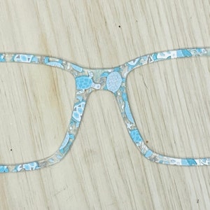 May include: A pair of blue and white patterned eyeglasses with a square frame.