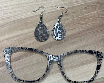 May include: A pair of black and white skeleton-themed earrings and a pair of black and white skeleton-themed glasses.