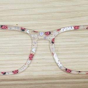 May include: Clear plastic eyeglasses with a square frame and ladybug and flower print.
