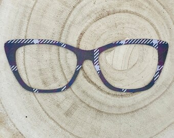 May include: Cat-eye shaped eyeglass frames featuring a dark purple and black plaid pattern with thin white diagonal stripes. The frames have a distinct pointed outer edge and a smooth, flat surface, showcasing a classic geometric design.