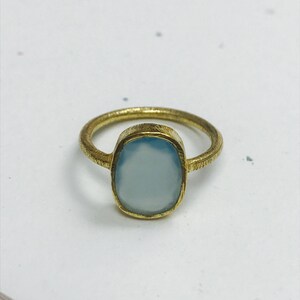 May include: A gold ring with a light blue oval gemstone.