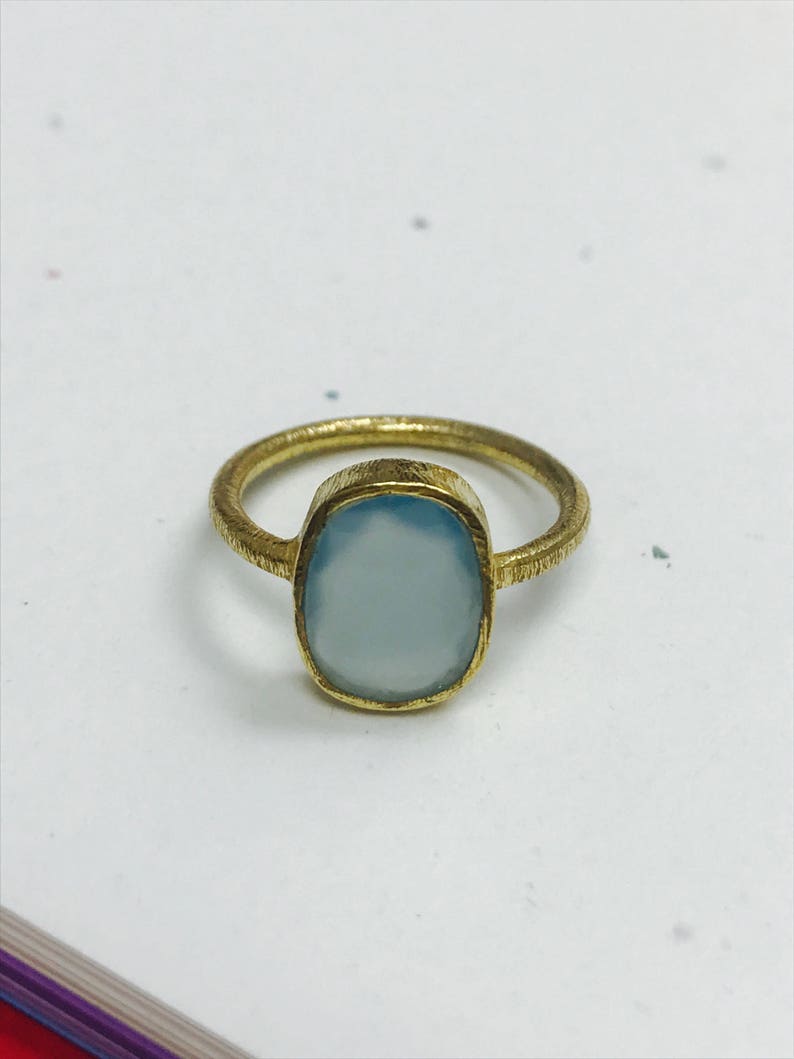 May include: A gold ring with a light blue oval gemstone.