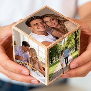 Könnte beinhalten: Ein hölzerner Fotowürfel mit Bildern eines Paares in verschiedenen Umgebungen. Der Würfel zeigt mehrere Fotos, darunter ein lächelndes Paar, beim Essen und beim Spaziergang in einem Park. Der Würfel wird in den Händen einer Person gehalten.