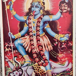 Può includere: Un'illustrazione colorata di Kali Mata, una dea indù, raffigurata con più braccia, un corpo blu e una ghirlanda di teschi. Lei sta in piedi su una figura sconfitta, tenendo una spada e una coppa di teschio. Lo sfondo è un paesaggio rosso e arancione.