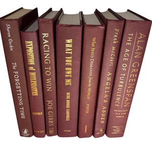 May include: A collection of seven hardcover books with burgundy covers and gold lettering. Titles include "The Forgetting Time," "Racing to Win," and "Angela's Ashes." The books are arranged in a slightly fanned-out display.