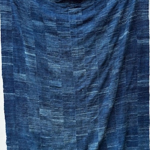 May include: A rectangular textile wall hanging featuring a deep indigo blue color palette. The fabric is composed of vertical panels stitched together, displaying a variegated, hand-dyed appearance with subtle horizontal striations.