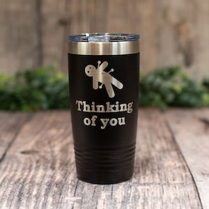 May include: Black stainless steel tumbler with a voodoo doll graphic and the text "Thinking of you".
