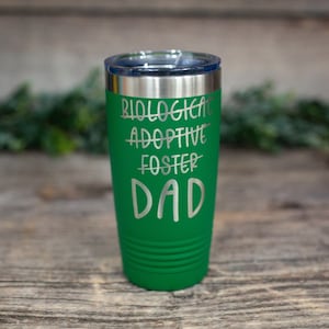 May include: Green stainless steel tumbler with the words "Biological, Adoptive, Foster" crossed out and "Dad" written below.