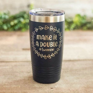 May include: Black stainless steel tumbler with a gold inscription that reads "Make it a double #twinmom" in a wreath design.