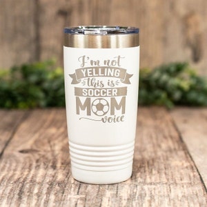 May include: White stainless steel tumbler with a gray engraved design that reads "I'm not yelling this is soccer mom voice" with a soccer ball graphic.