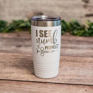 May include: White stainless steel tumbler with a black and white design that says "I see numb people" with a tooth and a syringe graphic.