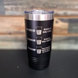 May include: Black stainless steel tumbler with a white inscription that reads "Optimist glass is half full, Pessimist glass is half empty, Engineer the glass is twice as big as it needs".