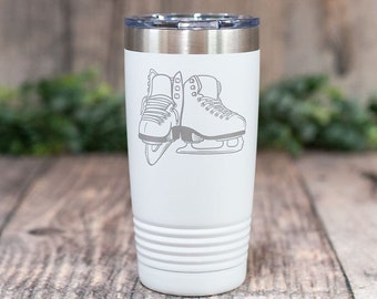 May include: White stainless steel tumbler with a gray outline of a pair of ice skates.