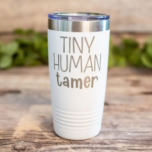May include: White stainless steel tumbler with the text "Tiny Human Tamer" in gray lettering.