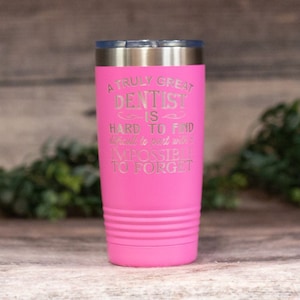 May include: A pink stainless steel tumbler with a silver lid. The tumbler has an engraved message that reads: "A truly great dentist is hard to find, difficult to part with, and impossible to forget."