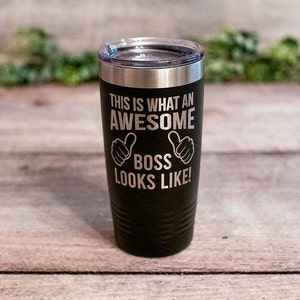 May include: Black stainless steel tumbler with a silver inscription that reads "This is what an awesome boss looks like!" with two thumbs up symbols on either side of the word "boss".