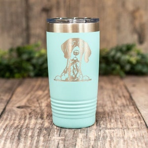 May include: A light blue stainless steel tumbler with a laser engraved image of a German Shorthaired Pointer dog peeking over the top.