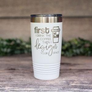 May include: White stainless steel tumbler with a silver lid. The tumbler has a graphic that says "first I drink the coffee. then I design your space" with a coffee cup icon.