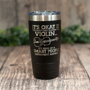 May include: Black insulated tumbler with a silver rim and lid. The tumbler has the text "IT'S OKAY IF YOU DON'T LIKE PLAYING THE VIOLIN... IT'S KIND OF A SMART PEOPLE INSTRUMENT ANYWAY" in white lettering, along with a violin graphic.