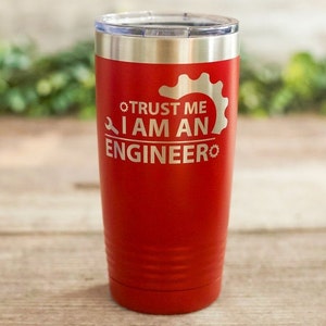 May include: Red stainless steel tumbler with a silver lid. The tumbler has a white inscription that reads "Trust me I am an engineer" with a wrench and gear graphic.