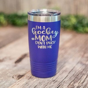 May include: Purple stainless steel tumbler with a white inscription that reads "I'm a hockey mom don't puck with me".