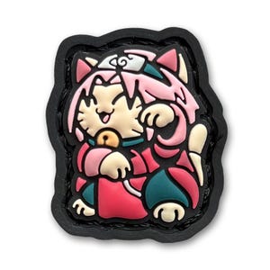 May include: A pink and red cartoon cat wearing a headband with a swirl design. The cat is holding a red and green object in its right paw. The cat is on a black background.