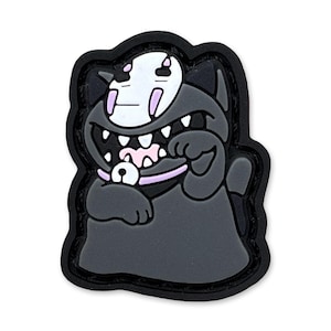 Puede incluir: Un parche de dibujos animados en blanco y negro que representa una criatura felina con una máscara blanca y dientes grandes. El parche tiene un borde negro y un collar rosa con una campana. La criatura está sonriendo y levantando su pata.