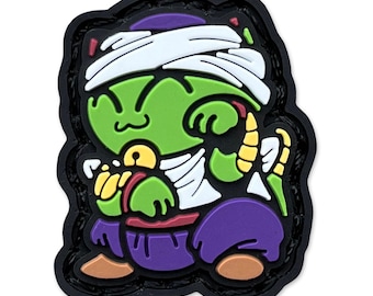 May include: A green cartoon character patch with a white head wrap, purple pants, and a black border. The character has yellow accents and is smiling. The patch is a fun, colorful accessory.