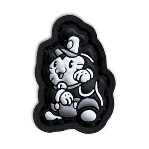 Puede incluir: Parche de dibujos animados en blanco y negro de un gato con un sombrero y sosteniendo un cubo. El parche está hecho de goma y tiene un borde negro.