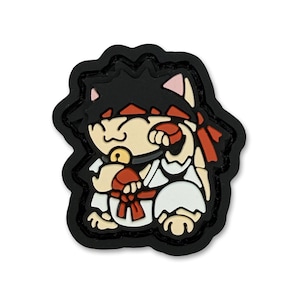May include: A cartoon-style patch featuring a cat character dressed as a martial artist. The cat has black hair, a red headband, and a white gi with a red belt. The patch is outlined in black.