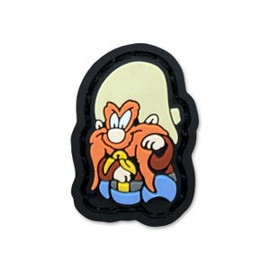 May include: A cartoon patch featuring Yosemite Sam. The patch has a black border and depicts the character with an orange mustache and eyebrows, a cream-colored hat, blue pants, and a yellow tie. The patch is on a white background.
