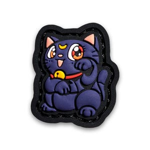 May include: A black and purple cartoon cat with a crescent moon on its forehead, wearing a red collar with a gold bell. The cat is sitting with its paws raised, as if it is waving. The cat is surrounded by a black border.