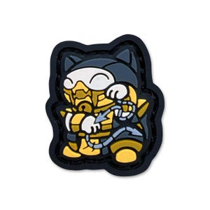 Peut inclure: Un charm en forme de chat noir, jaune et gris. Le charm représente un chat portant une tenue jaune et grise avec un masque blanc. Le chat tient une chaîne avec un motif de flèche. Le charm a une bordure noire.