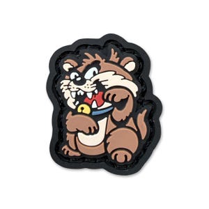 May include: A cartoon-style patch featuring a brown, tan, and white rodent with an angry expression. The rodent has a red tongue, a blue collar, and a gold bell. The patch has a black border and is set against a white background.