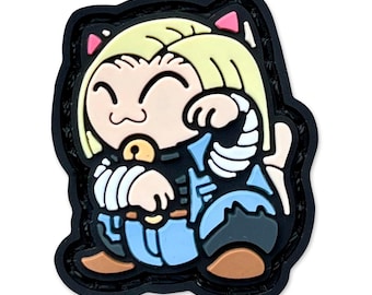 May include: A cartoon-style patch featuring a smiling cat-like character with blonde hair and pink cat ears. The character is wearing a blue outfit with white accents and a black outline. The patch has a black border.