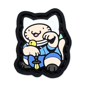 Könnte beinhalten: Ein farbenfroher Aufnäher mit einer Zeichentrickkatze in einem blauen Outfit, einem weißen Hut und einer gelben Glocke. Die Katze sitzt mit erhobener Pfote. Der Aufnäher hat einen schwarzen Rand und befindet sich auf weißem Hintergrund.