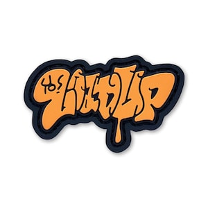 Puede incluir: Un parche naranja y negro con la palabra "SHADYSP" en letras de estilo graffiti. Las letras son de color naranja con un contorno negro, sobre un fondo negro.