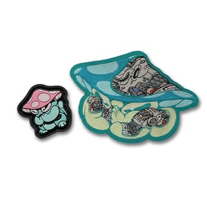May include: Two embroidered patches. One features a cartoon mushroom with a pink cap and a teal body. The other patch is a blue mushroom with a detailed robotic design inside. Both patches have a black border.